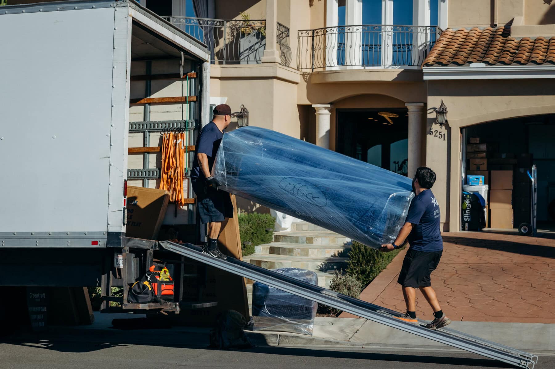 Movers navigating a heavy furniture piece down a ramp at a San Diego home.
